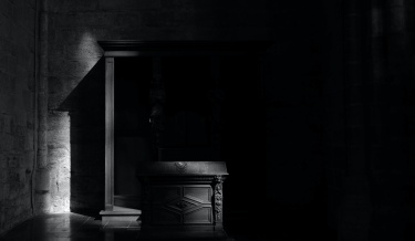 The
                stone walls and carved wood of the darkened monastery's
                interior.