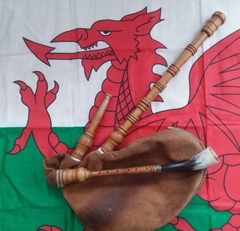 Welsh
                bagpipes laying on the red dragon of the Welsh flag.