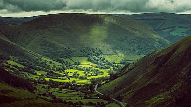 A sunny Welsh valley with storm clouds gathering