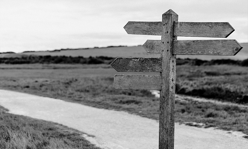 Old wooden crossroads sign, along a dirt road